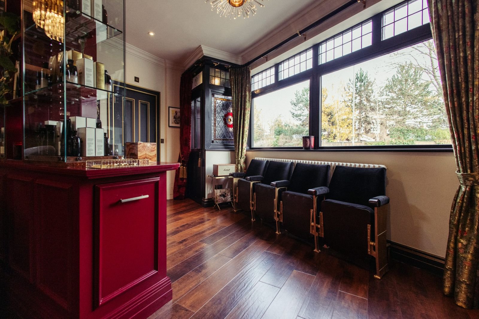 Salon interior with black leather seating beneath tall windows and a red cabinet
