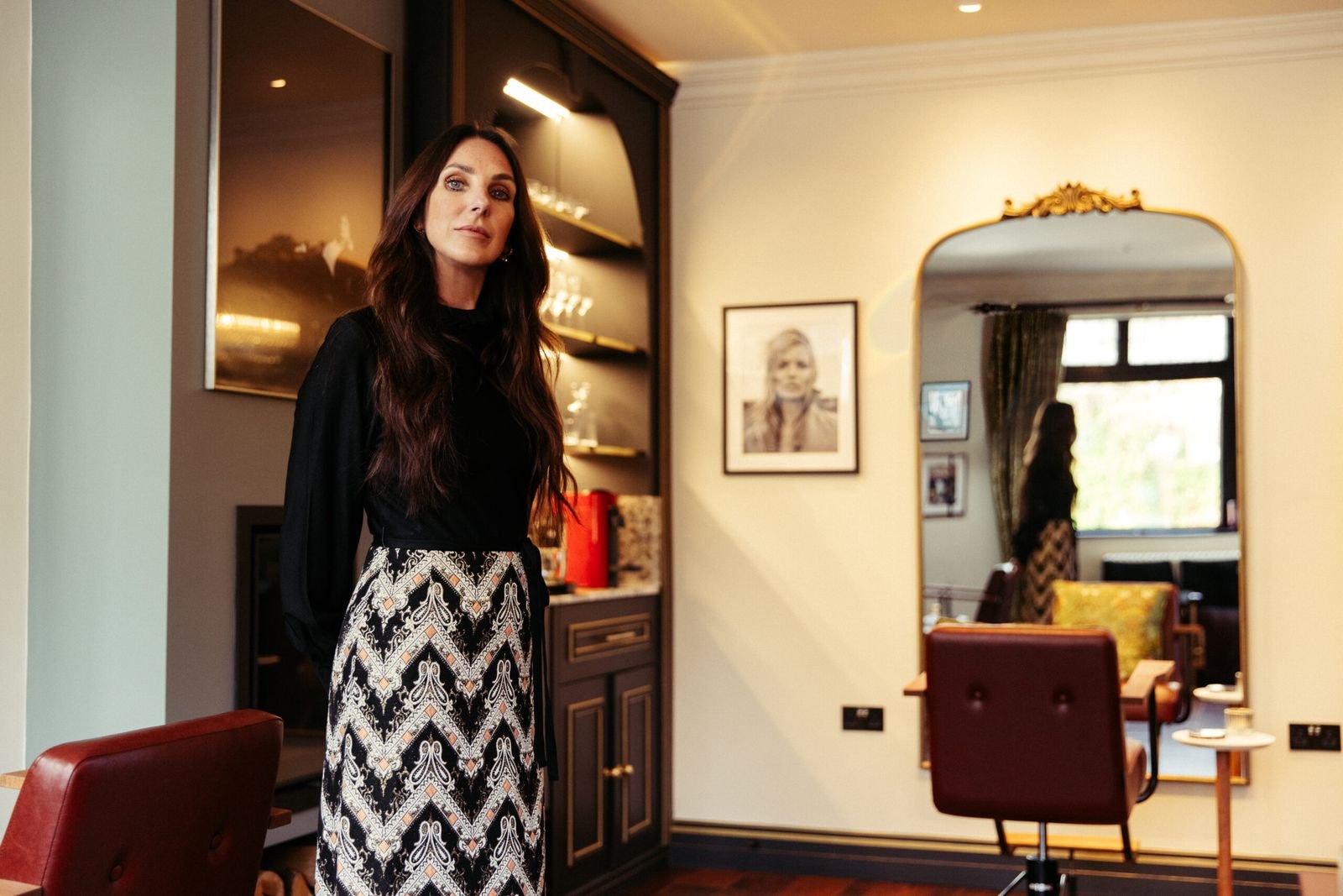 Sally O’Neill in the Behind the Curtain salon beside an arched gilt mirror