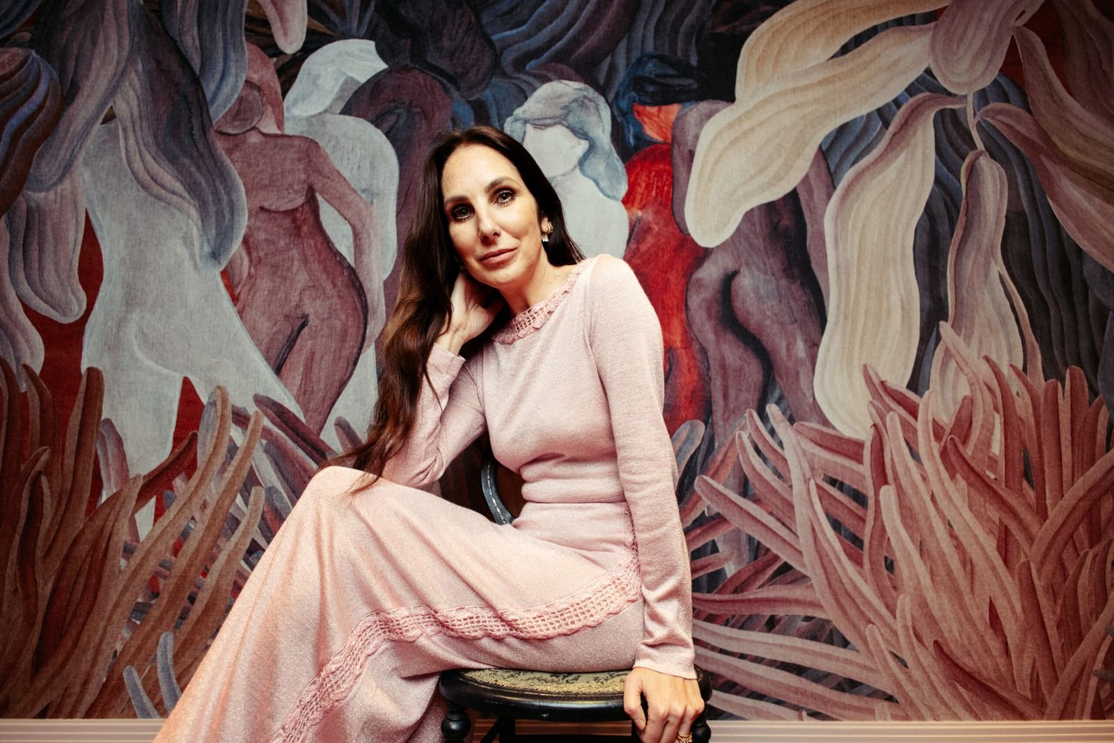 Sally O’Neill seated in front of a painted botanical mural
